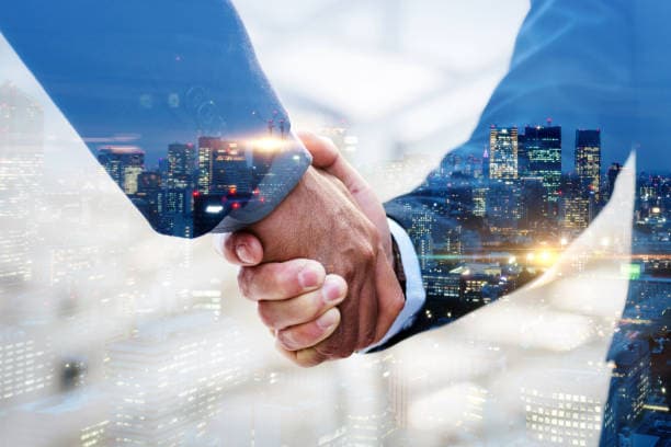A handshake over a city skyline at night